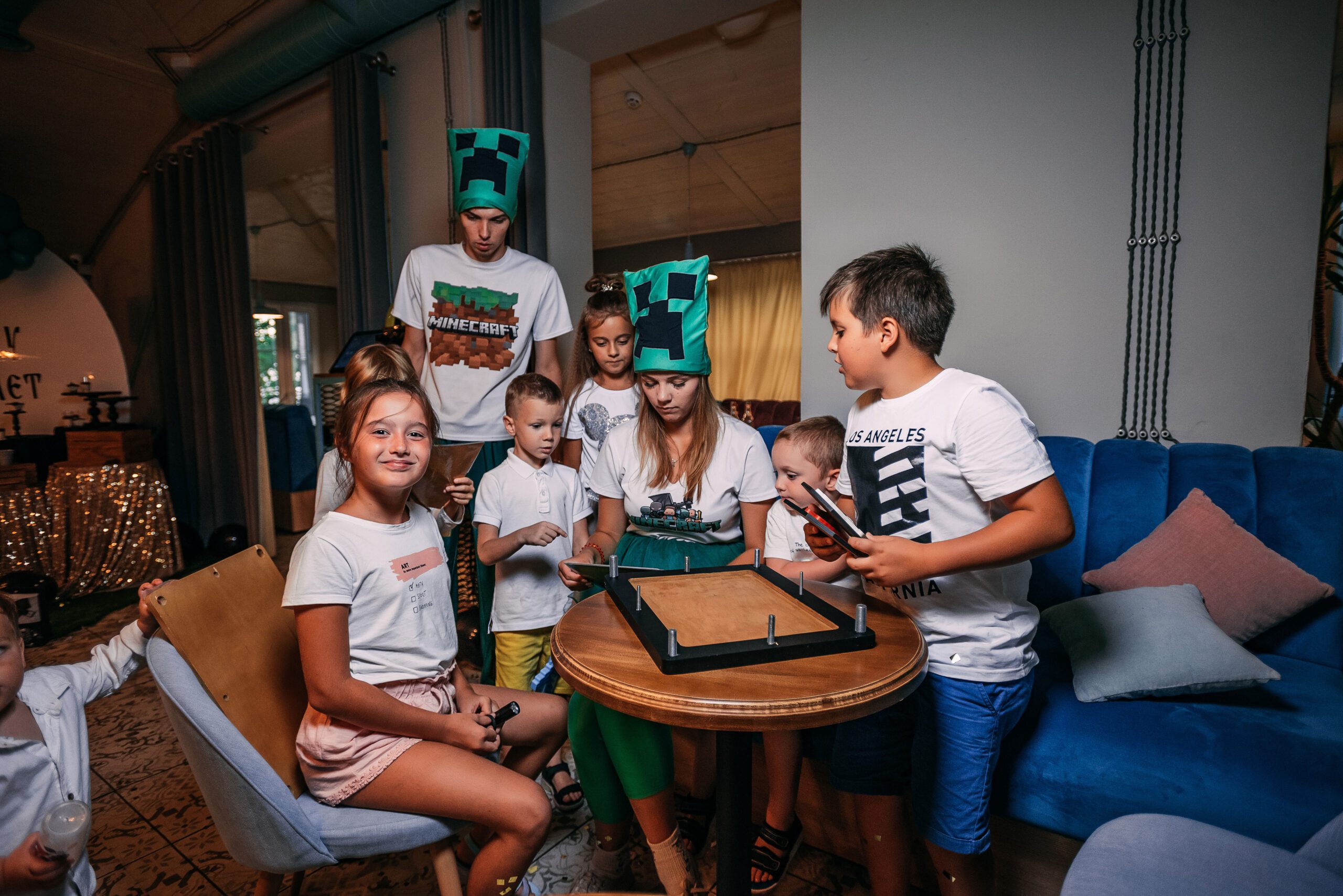 Kids with two costumed hosts assemble a framed puzzle with bolts during the mission briefing.