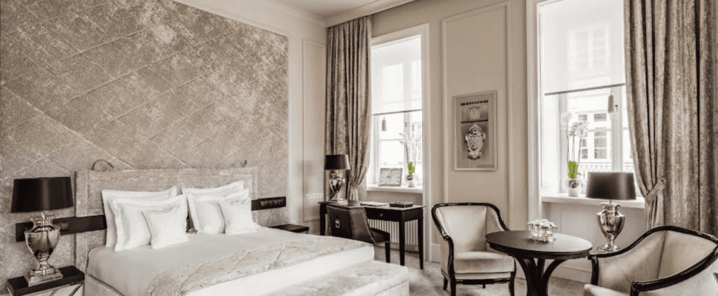 Elegant hotel room with neutral decor, large bed and seating area.