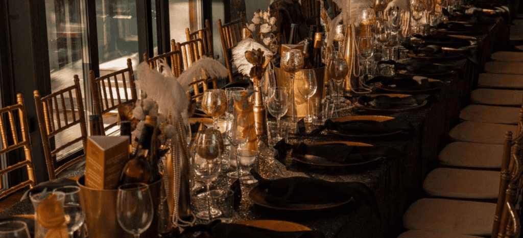 Elegant black and gold dinner table setup with decorative feathers and glassware.