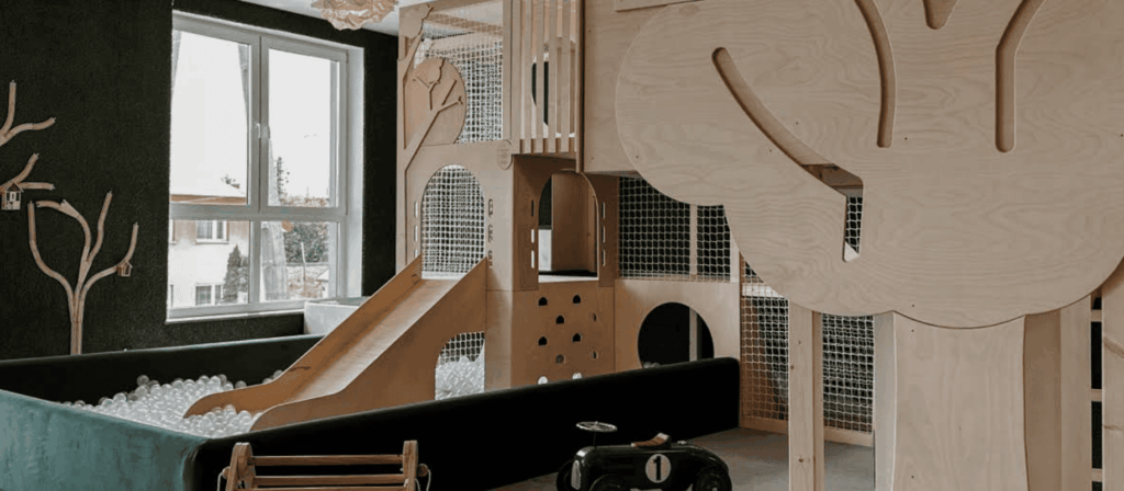 Wooden indoor playground with slide, ball pit, and forest-inspired decorations creating a calm, nature-themed play area.