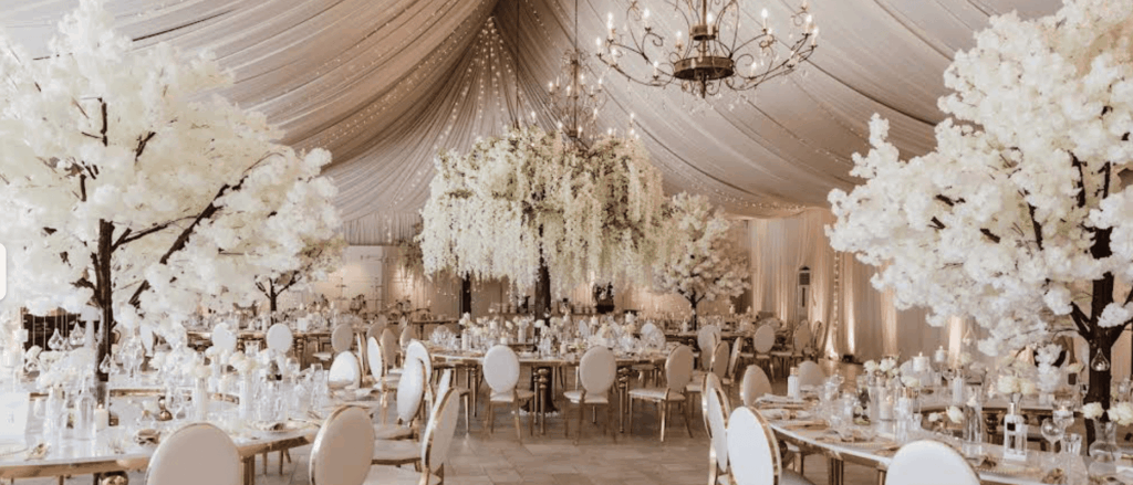 Luxurious event hall decorated with white flowers and chandeliers.