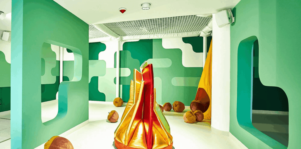 Sensory playroom with soft geometric walls, bean bags, and creative structures encouraging exploration and imagination.